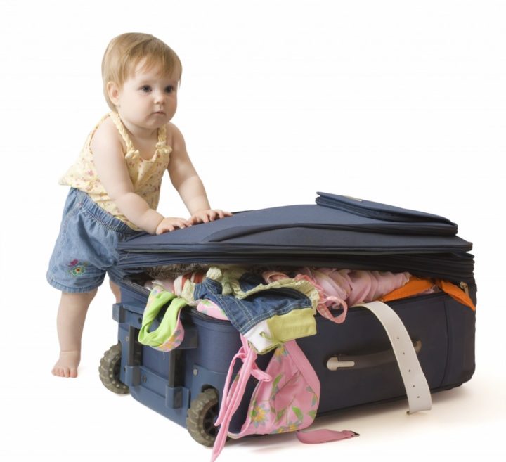 Baby standing near the suitcase