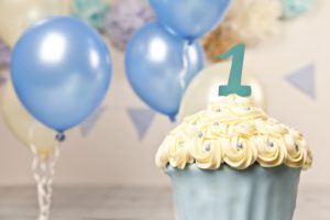 Giant beautifully decorated blue and cream cup cake surrounded by bunting and balloons.