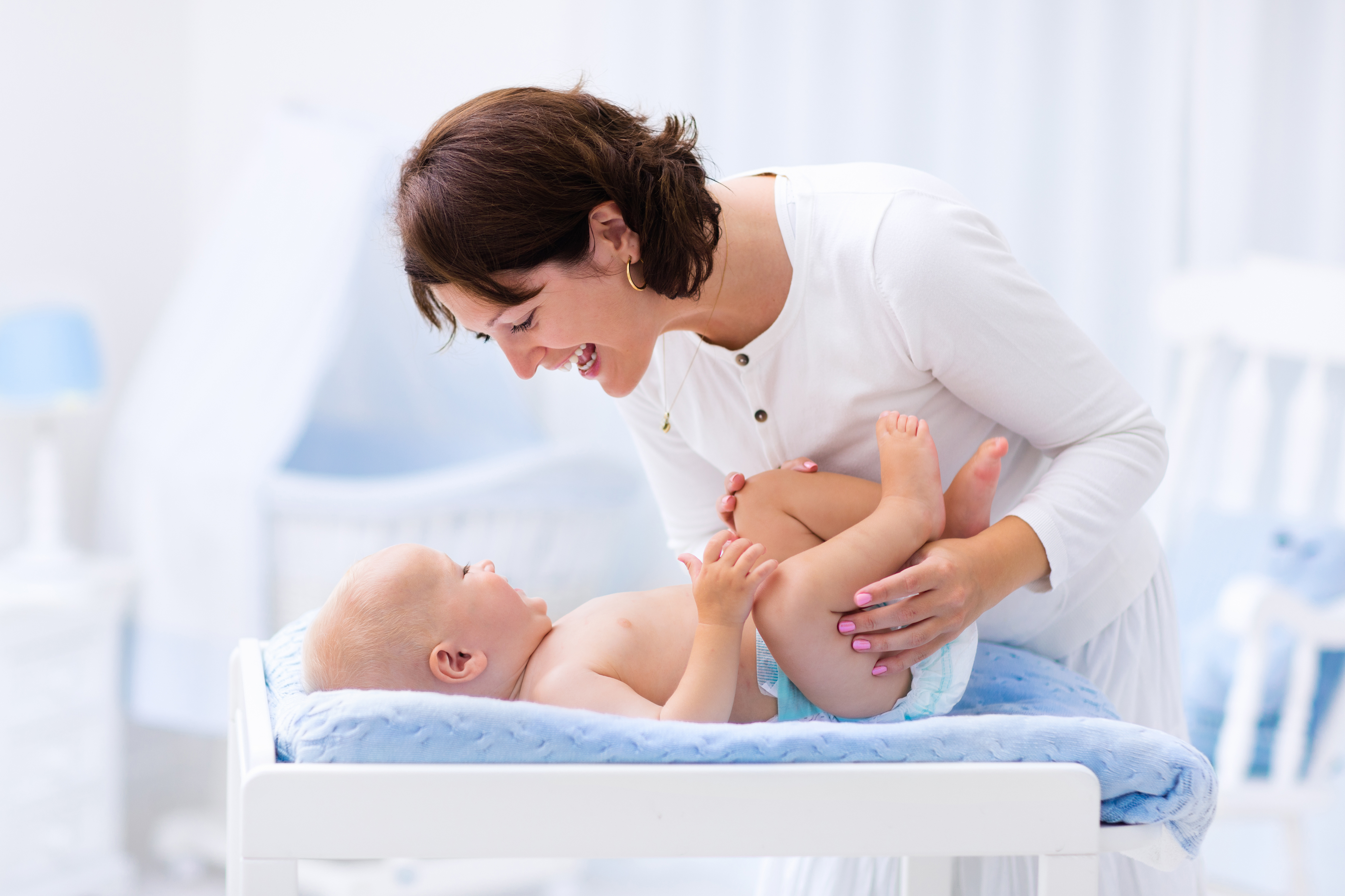 Mother and baby on changing table in beautiful bedroom