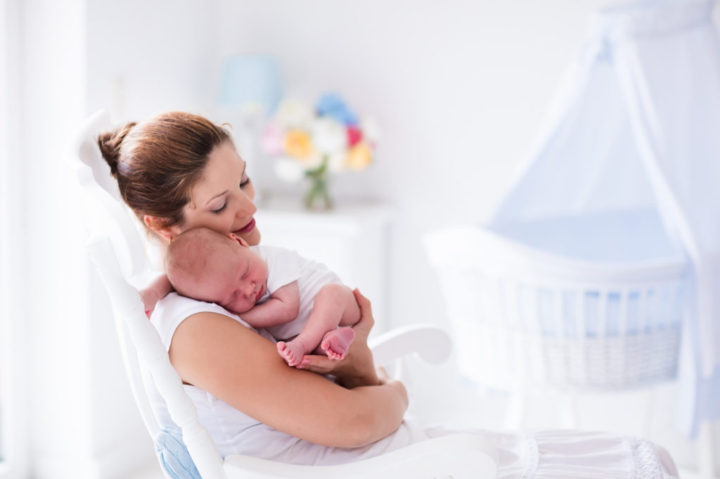 Mother and newborn baby in white nursery