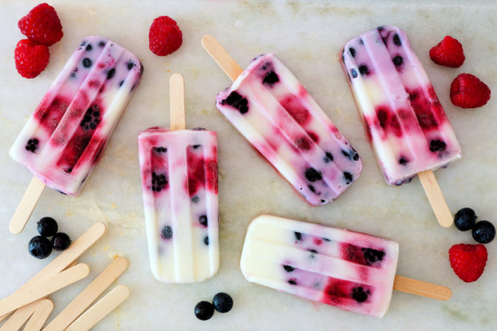 Mixed berry yogurt popsicles on white marble
