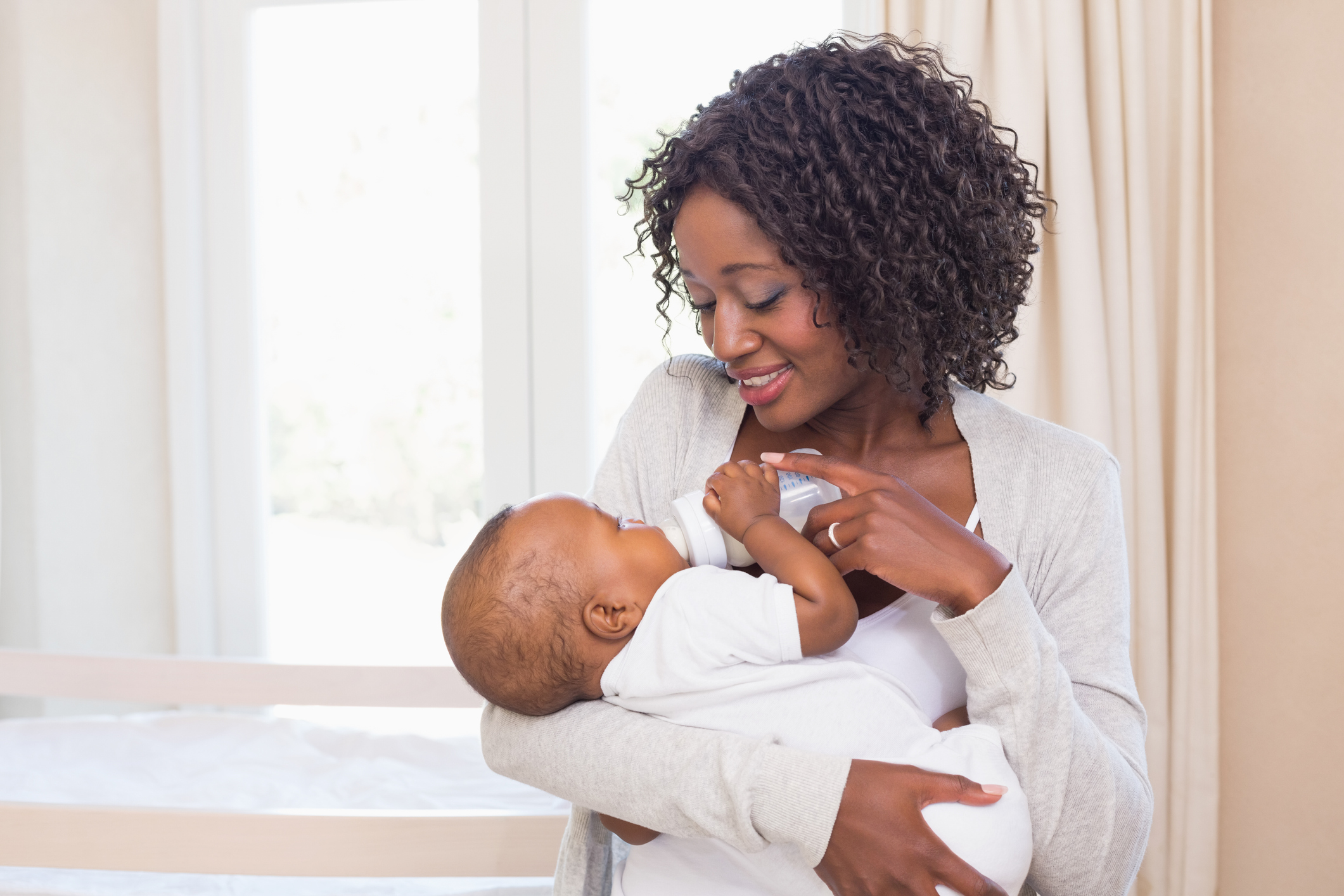 Happy mother feeding her baby boy his bottle