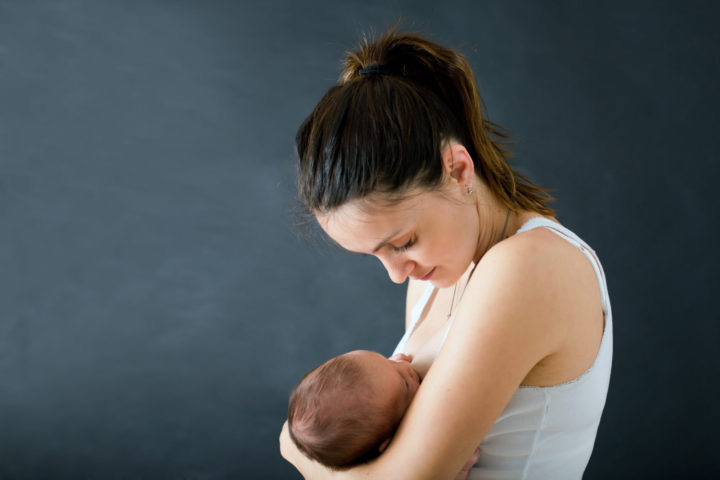Young mother, breastfeeding her newborn baby boy