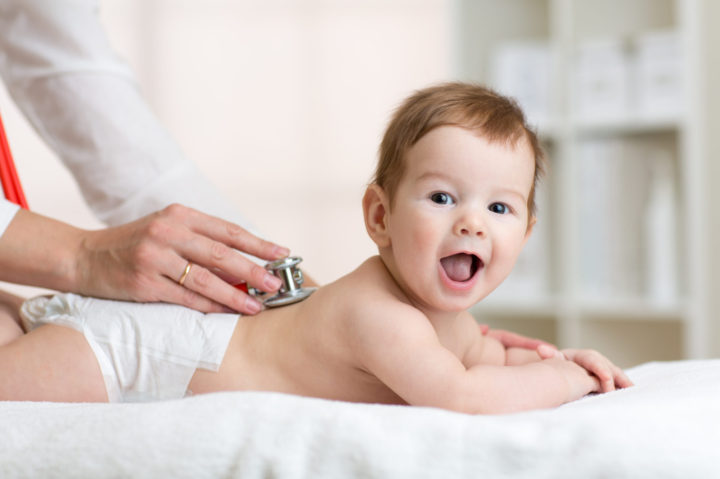 Pediatrician examining baby. Doctor using stethoscope listen to kid back